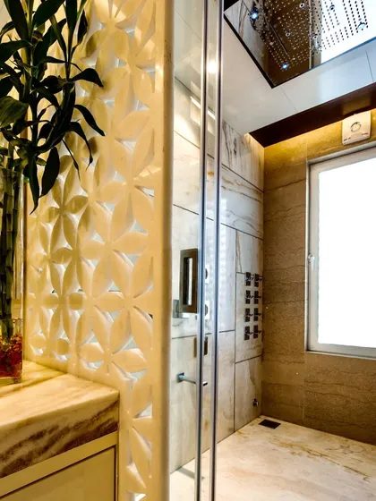 The details are what make the design. This bathroom features a custom-carved marble accent wall with a floral pattern, adding a delicate and artistic touch to the shower area.