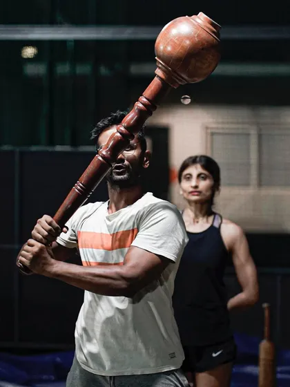 A coach guiding a member through a Gada swing. It's about learning the technique and respecting the weight. This is where strength and skill come together.