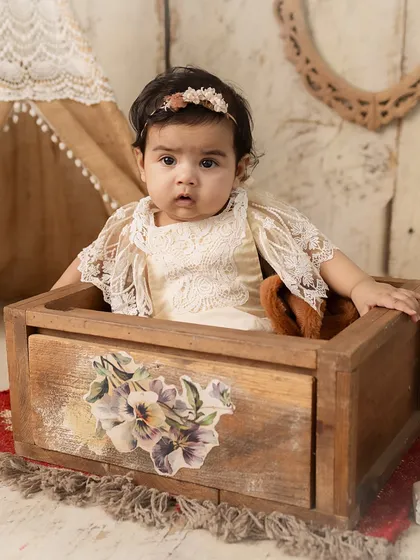 A creative shot of the baby peeking out of a rustic wooden box.