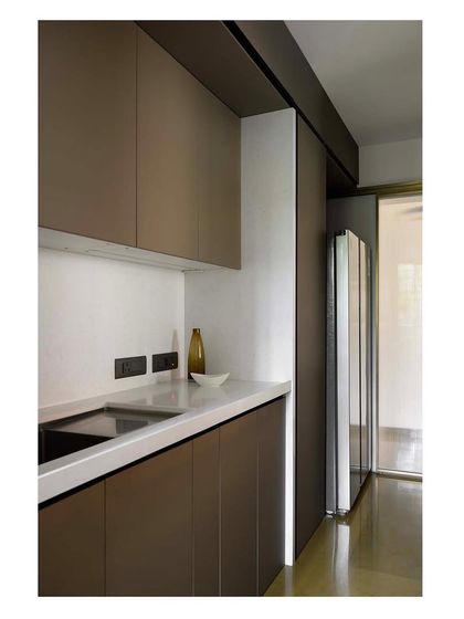 Another angle of the minimalist kitchen, showing the seamless integration of the refrigerator and overhead storage, all designed to maximize efficiency and maintain a clutter-free look.