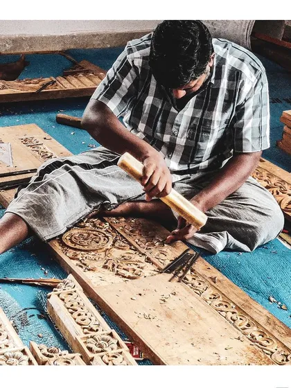 Our design philosophy is hands-on. Here, a master carpenter chisels intricate patterns into a wooden panel on-site, a testament to our commitment to preserving and promoting traditional craftsmanship in our projects.