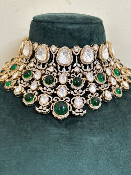A close-up of a choker necklace combining large Kundan stones with smaller green gems. This rental piece is available for any festive occasion.