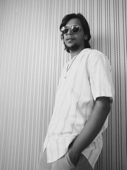 A cool and casual black and white shot of another actor from the Kota Factory team, styled in a relaxed, striped shirt.