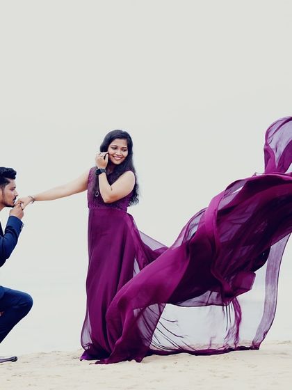 A classic "proposal" pose on the beach. The dramatic, flying trail of the purple gown adds a fairytale quality to this romantic pre-wedding moment.
