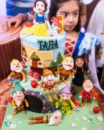 The adorable Tara, daughter of Mahhi Vij and Jay Bhanushali, dressed as Snow White for her 5th birthday, posing with her magnificent rotating cake featuring all seven dwarfs.