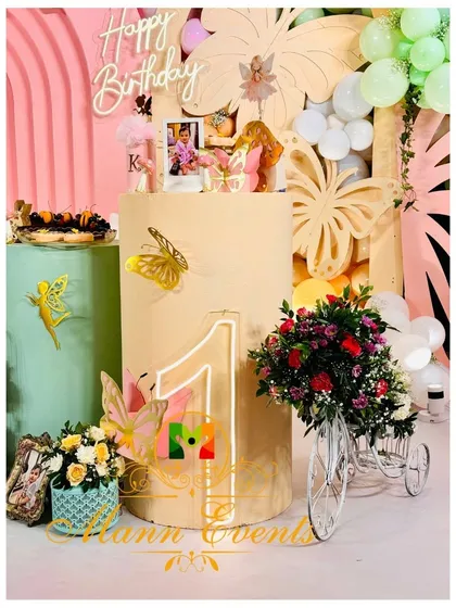 A detail shot from a first birthday party, showing a neon '1' sign, a miniature floral tricycle, and other carefully placed props that add charm and personality.