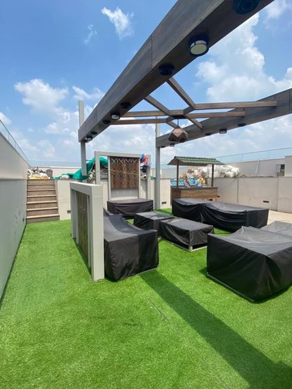 Another angle of the Gurugram rooftop lounge, showing the extensive artificial turf installation that provides a resort-like feel to this urban space.