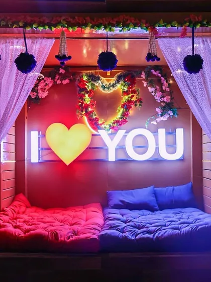 Here is a closer look at one of our romantic setups, complete with plush floor seating and an "I Love You" sign. It's designed to be a comfortable and intimate space for you and your partner to relax.