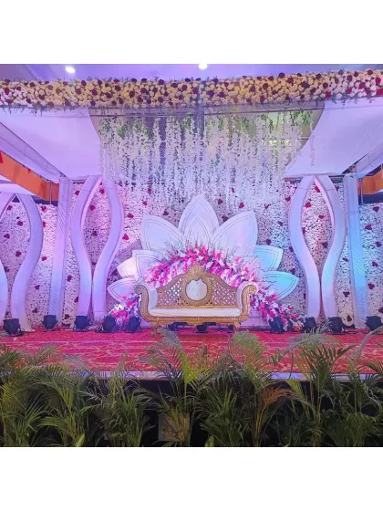 A full view of the lotus-themed wedding stage. Surrounded by potted plants, the stage combines a traditional floral canopy with modern sculptural elements and lighting, showing how we can blend different styles to match your vision.