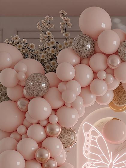 Another perspective on the balloon garland, showing how different sizes and finishes of balloons are layered to create a sense of depth and luxury. The neon butterfly outline adds a glowing, thematic element to the composition.