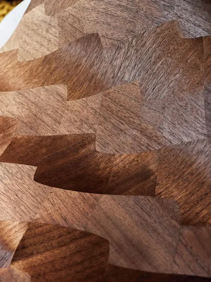 A close-up of our wood marquetry wallpaper, showcasing the grain and texture of the paper-thin slices of paulownia. Light and shadow weave an evocative narrative across the undulating surface.
