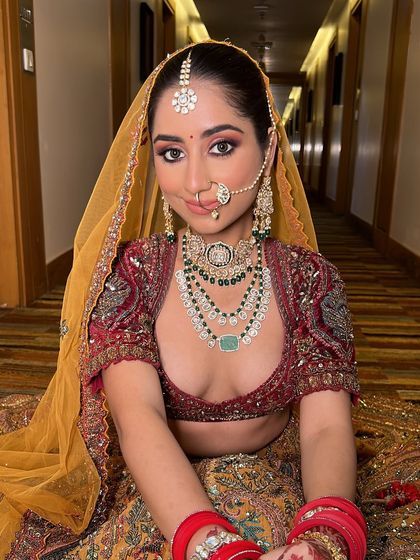 A full shot of the bride sitting gracefully. The yellow dupatta adds a beautiful pop of color, and her makeup ties the whole look together perfectly.