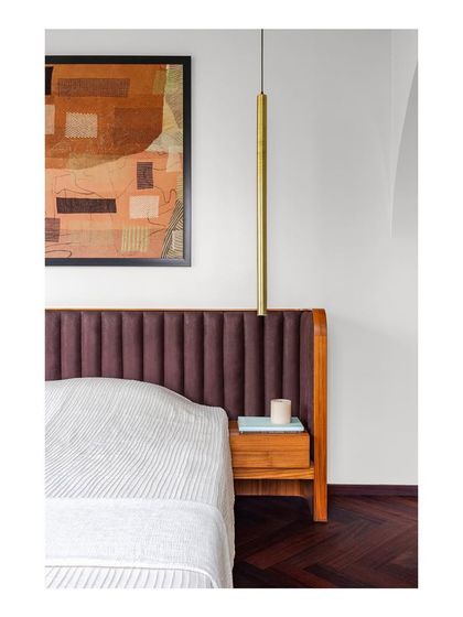 A detailed view of the master bed, with its rich brown upholstered headboard and integrated wooden nightstand. I focus on layers of texture and warm tones to create a comfortable and inviting bedroom.