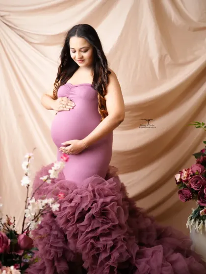 A solo portrait of the mother-to-be, gently cradling her bump. The unique texture of the gown's train adds a touch of high-fashion glamour to the shot.