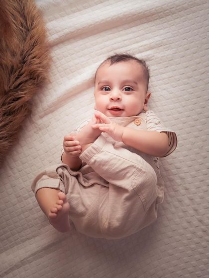 Those eyes! This overhead shot on a simple white textured background is perfect for capturing a baby's playful discovery of their own feet.
