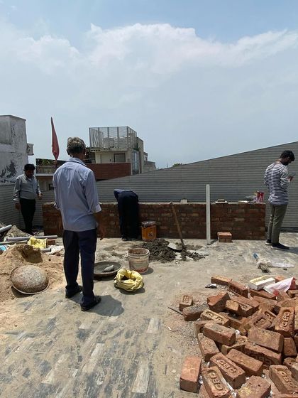 The process often involves foundational civil work. Here, our team is building a brick wall on a rooftop, which will later become part of a planter bed or a boundary for a new seating area.