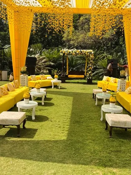A symmetrical view of a Haldi seating area, showing the arrangement of long sofas and ottomans. The decor is consistently bright and sunny, perfect for a daytime event.
