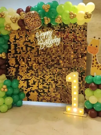 A jungle-themed first birthday with a gold shimmer wall, a '1' marquee light, and a giraffe cutout.
