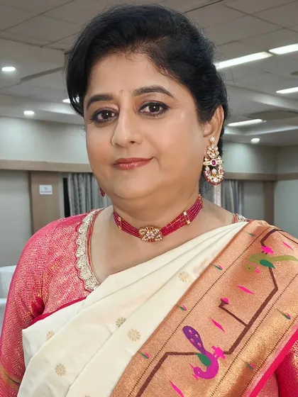 The mother of the bride looking chic and happy at the Haldi ceremony. Her look features a classic updo with a fresh flower, paired with simple makeup and cool sunglasses for the outdoor event.