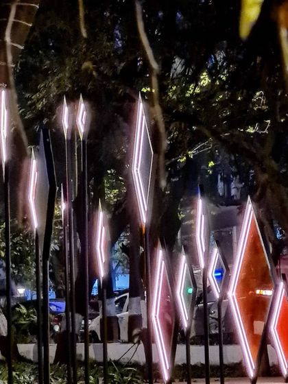 A side view of the 'Family Tree' at night, with its glowing geometric frames set against the dark foliage. This juxtaposition of technology and nature is a recurring theme in our work.