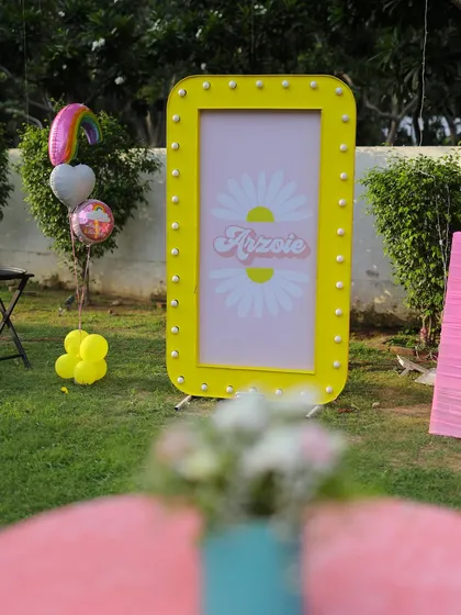 Another shot of the yellow daisy marquee sign, with rainbow-themed balloons nearby. This piece serves as a fantastic photo prop and decorative element.