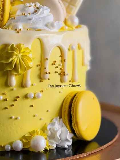 A detail shot of the white chocolate drip and yellow macarons on the sunny birthday cake.