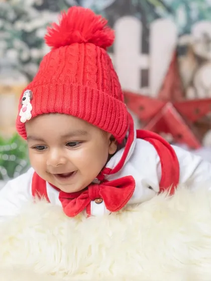 A happy baby enjoying tummy time on a soft fur rug amidst a snowy, festive scene. Capturing these milestone movements is so important.