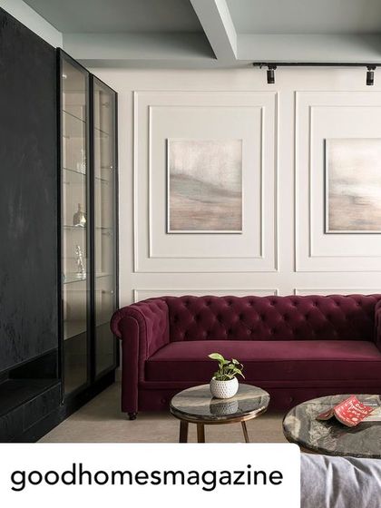 A close-up of the living room with a burgundy Chesterfield sofa and a black display cabinet. The design layers different textures and colors to create an interesting and eclectic English-inspired style.