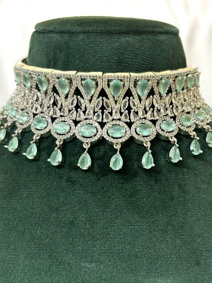 A silver-toned choker with mint green stones and American diamond accents. This is a fresh and modern rental piece.