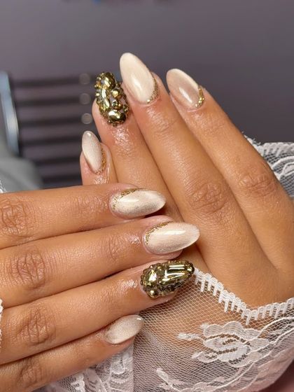 For the client who loves to sparkle. This design features a soft cat-eye base with two accent nails completely covered in large, statement gold crystals.