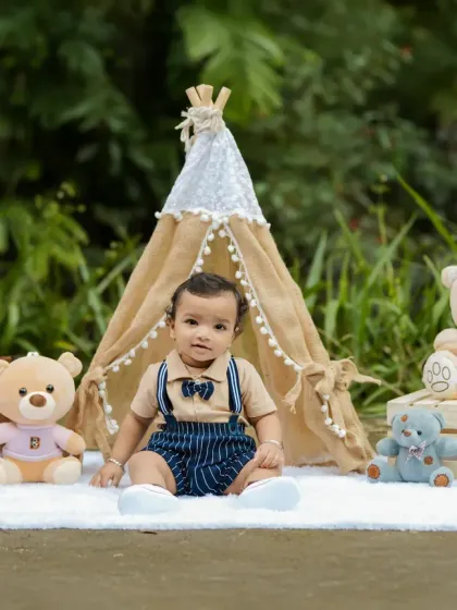 A classic outdoor first birthday setup with a teddy bear picnic theme. The natural greenery provides a beautiful, soft background.
