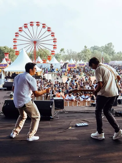 Rocking out on stage with my bandmate at Zomaland in Bangalore. Daytime festivals have such a unique, fun energy. You can see the ferris wheel and the huge crowd, it was an unforgettable day.