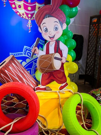 A prop of a boy playing a dhol, adding to the festive and musical theme of the party.