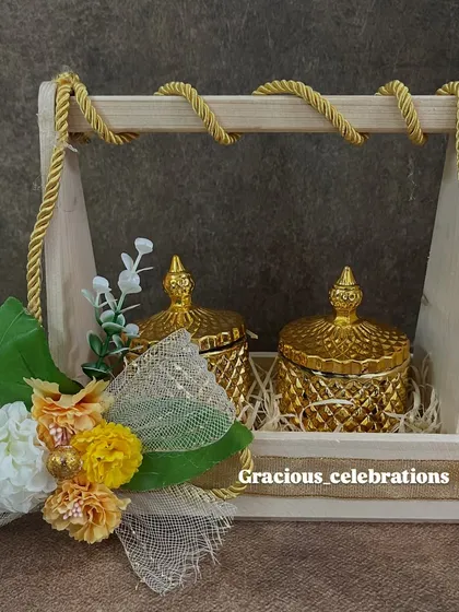 This wooden caddy with two golden crystal jars is a beautiful and budget-friendly return favor for weddings. It can be filled with dry fruits or other treats and is decorated with floral accents.