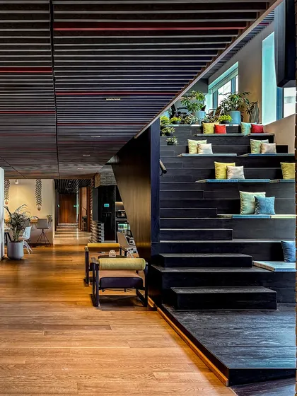 The stepped seating of the amphitheater at BCG HQ is adorned with plants and colorful cushions, turning a functional space into a vibrant, living part of the office.