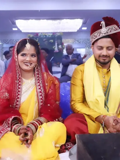 The couple seated during the wedding ceremony, participating in the rituals.