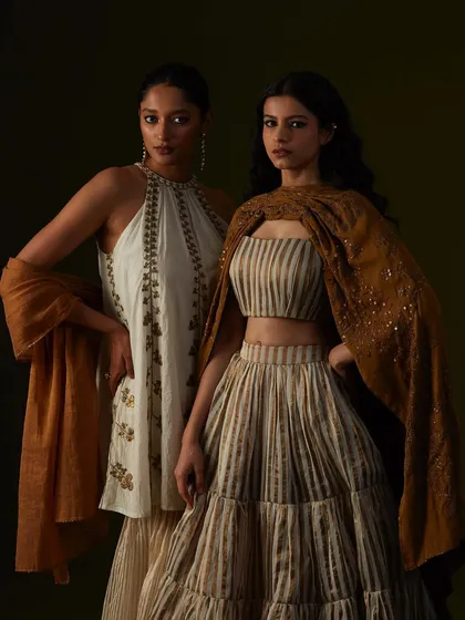A dual-model shot against a dark, moody background. The lighting is carefully placed to create a dramatic, painterly effect.