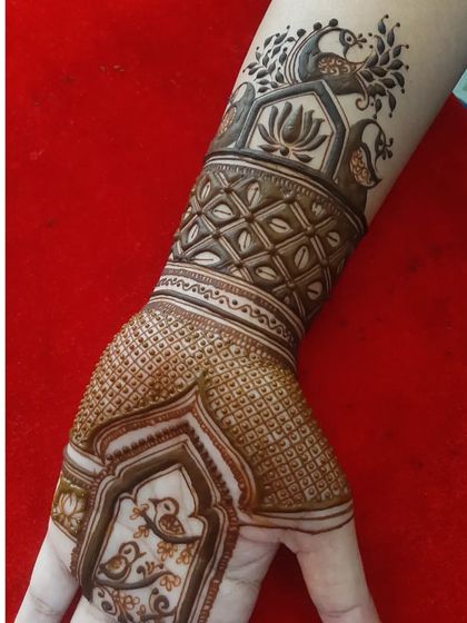This custom engagement mehendi includes charming love birds inside a decorative frame. The wristband above features a lotus and peacock design.