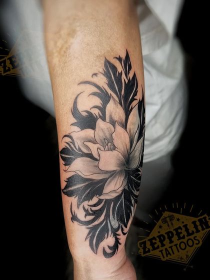 The final result of the floral cover-up on the forearm. The contrast between the light petals and dark leaves creates a dynamic effect that completely hides the old tattoo.