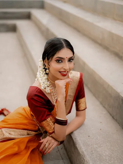 A relaxed portrait of a model in a traditional saree, lying on stone steps. The unusual pose and soft lighting create a unique and artistic shot.