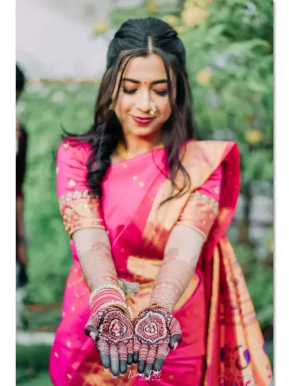 The bride showing off her engagement mehendi, with the dark stain looking perfect with her bright pink saree.