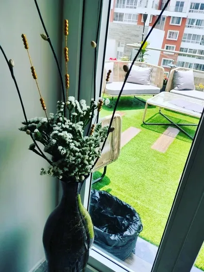 A dried floral arrangement in a dark vase, perfect for a long-lasting decorative piece. This setup, seen against a balcony view, shows how I use different textures and materials for home styling.