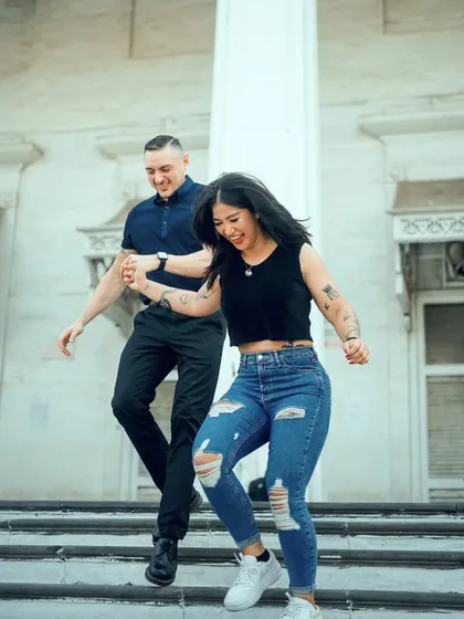A joyful, candid shot of a couple dancing down the stairs. Their happiness is infectious in this energetic urban pre-wedding photo.
