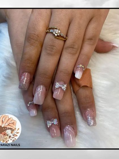 A soft, feminine look with a marbled pink base, glitter accents, and sparkling 3D rhinestone bows.