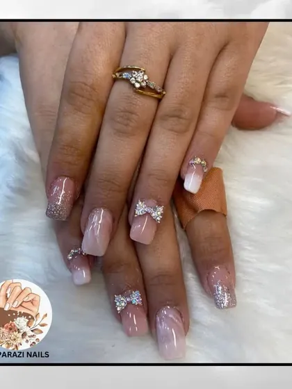 A soft, feminine look with a marbled pink base, glitter accents, and sparkling 3D rhinestone bows.