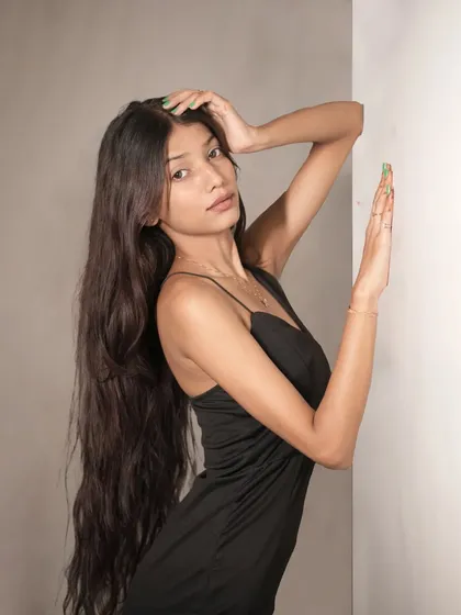 An artistic pose with the model's arms raised, creating elegant lines that complement the form-fitting black dress.