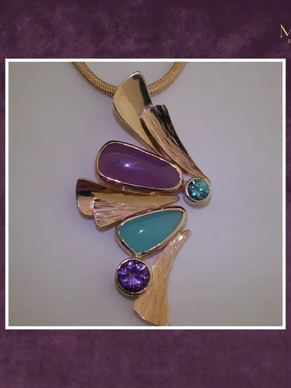 Bold, vibrant, and full of life. This abstract pendant combines turquoise, amethyst, and other purple stones in a striking gold setting, making it a perfect statement piece.