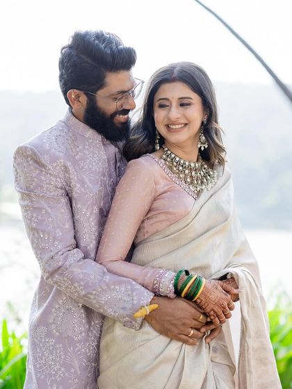 A beautiful reception look for a real couple. The bride is elegant in a simple off-white saree with a statement necklace, while the groom complements her perfectly in a lavender chikankari sherwani.