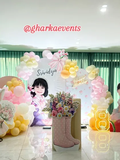 A personalized birthday setup featuring cute caricatures of the birthday girl. The decor includes pastel balloon arrangements, a bunny cutout, and a unique boot-shaped plinth for a touch of whimsy.