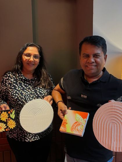 A couple proudly displaying the texture art pieces they created in one of my workshops. They made both a floral canvas and a circular textured board, showcasing the variety of techniques taught.